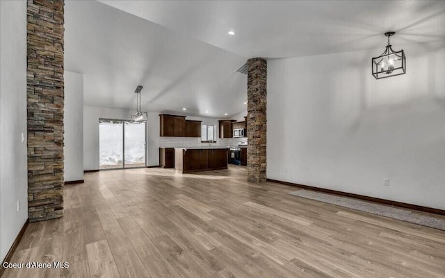 unfurnished living room with light wood-type flooring, vaulted ceiling, and an inviting chandelier