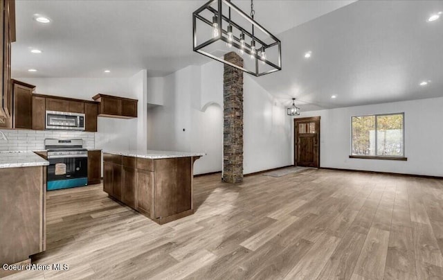 kitchen featuring stainless steel appliances, light hardwood / wood-style floors, a center island, high vaulted ceiling, and light stone countertops