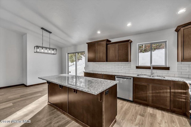 kitchen with sink, tasteful backsplash, decorative light fixtures, stainless steel dishwasher, and light wood-type flooring