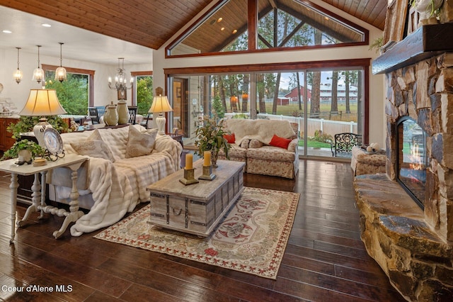 living room with dark wood-type flooring, a chandelier, wood ceiling, and a stone fireplace