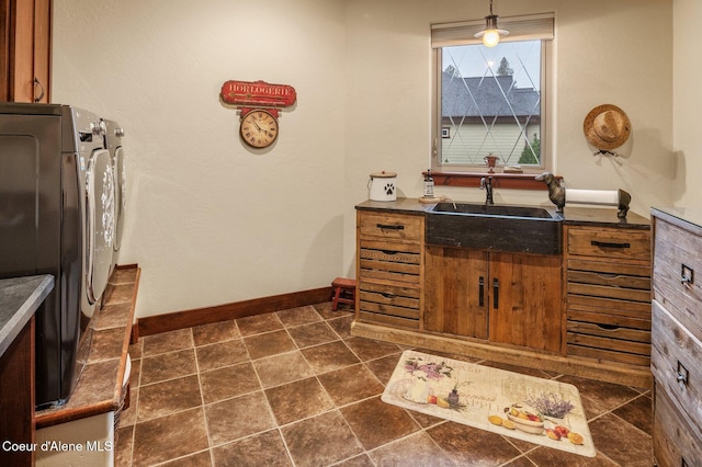 kitchen featuring hanging light fixtures, washing machine and dryer, sink, and dark tile patterned floors