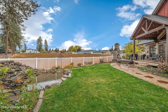 view of yard featuring a patio and an outdoor stone fireplace