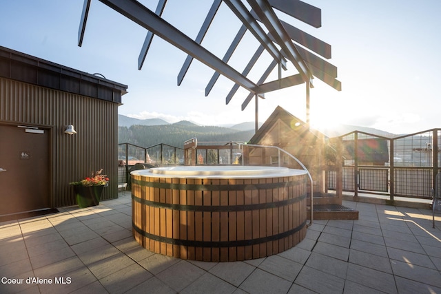 view of patio / terrace with a hot tub, a mountain view, and a pergola