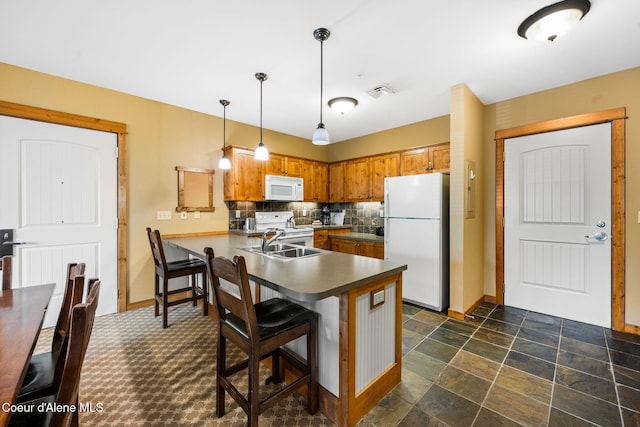 kitchen with tasteful backsplash, white appliances, a kitchen bar, pendant lighting, and kitchen peninsula