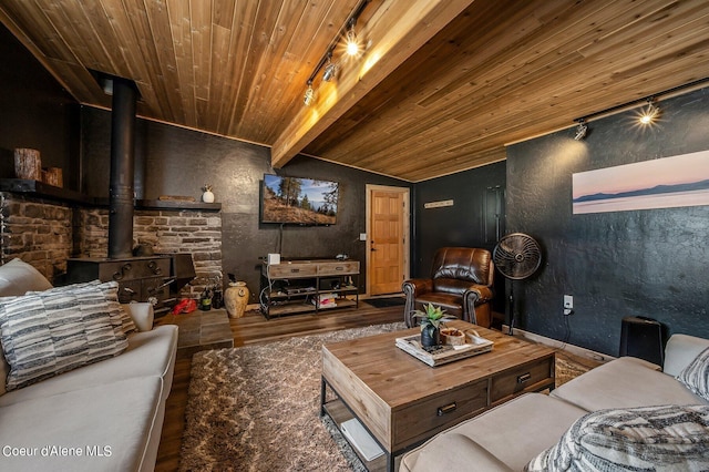 home theater featuring vaulted ceiling with beams, a wood stove, wood ceiling, hardwood / wood-style floors, and rail lighting