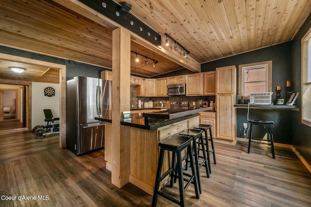 kitchen with track lighting, stainless steel appliances, a breakfast bar, and dark hardwood / wood-style flooring