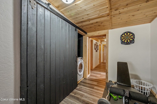 clothes washing area with wooden ceiling, wood-type flooring, washer / clothes dryer, and a barn door