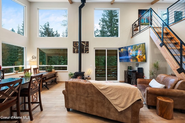 living room featuring a high ceiling, light hardwood / wood-style floors, and a wood stove