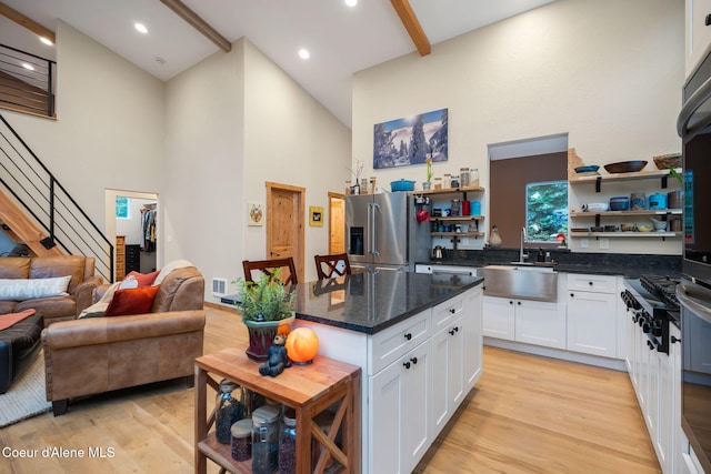 kitchen with stainless steel appliances, sink, high vaulted ceiling, light hardwood / wood-style floors, and white cabinetry