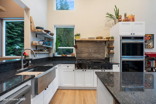 kitchen with dark stone counters, sink, light hardwood / wood-style flooring, white cabinetry, and stainless steel appliances