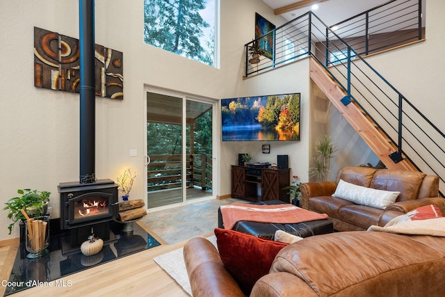 living room with hardwood / wood-style flooring, a wood stove, and a high ceiling