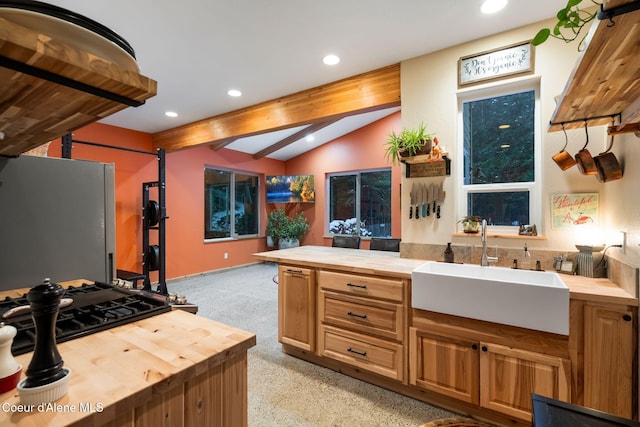 kitchen featuring stainless steel fridge, vaulted ceiling with beams, butcher block counters, and sink