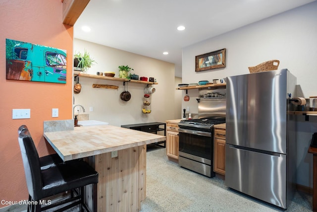 kitchen with sink, a breakfast bar area, light brown cabinetry, butcher block countertops, and stainless steel appliances