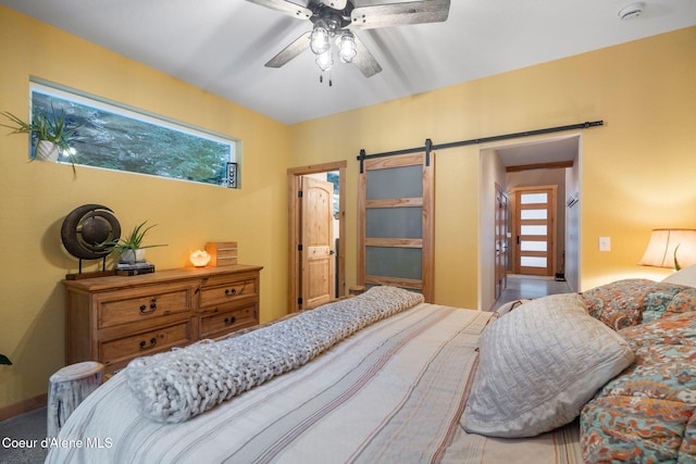 carpeted bedroom with a barn door and ceiling fan