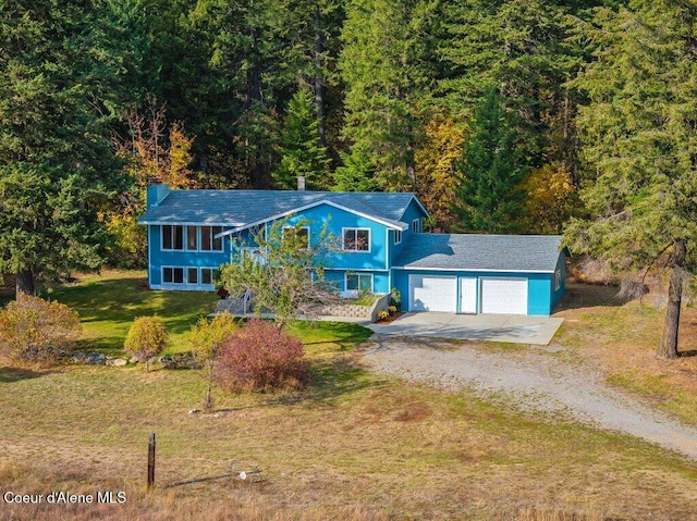 14895 N Crystal Springs Ln, Rathdrum, ID 83858 - view of front of house with driveway, an attached garage, a front lawn, a chimney, and a wooded view