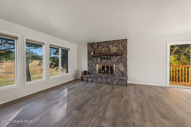 14895 N Crystal Springs Ln, Rathdrum, ID 83858 - unfurnished living room with plenty of natural light, wood finished floors, baseboards, and a stone fireplace