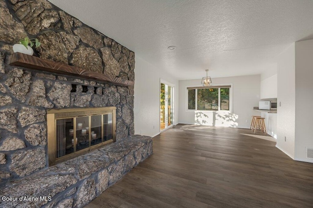 14895 N Crystal Springs Ln, Rathdrum, ID 83858 - unfurnished living room with wood finished floors, a fireplace, a textured ceiling, and baseboards