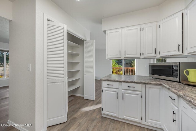 14895 N Crystal Springs Ln, Rathdrum, ID 83858 - kitchen with stainless steel microwave, white cabinets, wood finished floors, and plenty of natural light