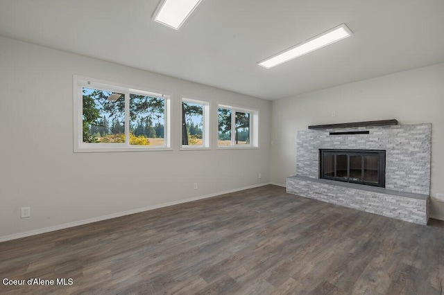 14895 N Crystal Springs Ln, Rathdrum, ID 83858 - unfurnished living room with healthy amount of natural light, wood finished floors, a stone fireplace, and baseboards