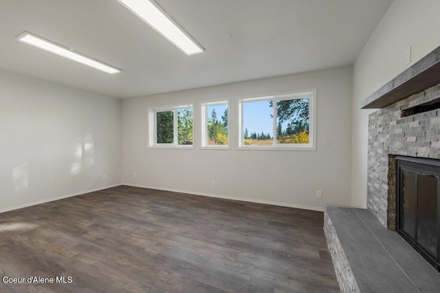 14895 N Crystal Springs Ln, Rathdrum, ID 83858 - unfurnished living room with a stone fireplace, dark wood-type flooring, and baseboards