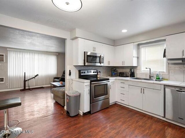 kitchen with dark hardwood / wood-style flooring, white cabinetry, sink, and stainless steel appliances