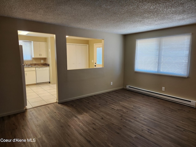 spare room with sink, light wood-type flooring, a textured ceiling, and baseboard heating