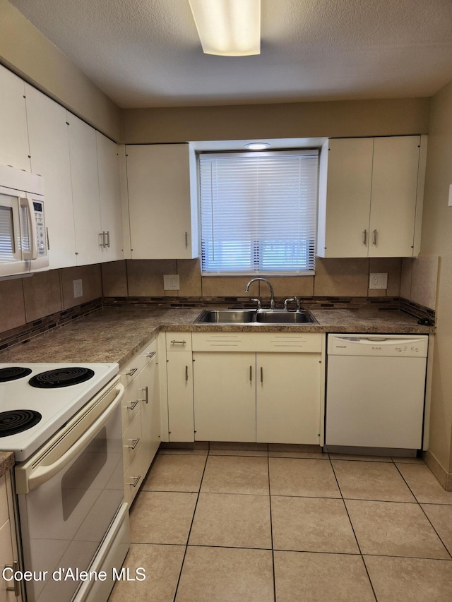 kitchen with light tile patterned flooring, a textured ceiling, sink, white cabinets, and white appliances