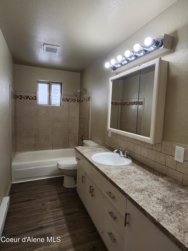 full bathroom with tiled shower / bath combo, decorative backsplash, hardwood / wood-style flooring, and a textured ceiling