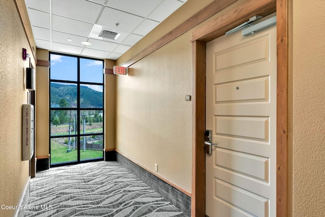 corridor with a paneled ceiling and carpet