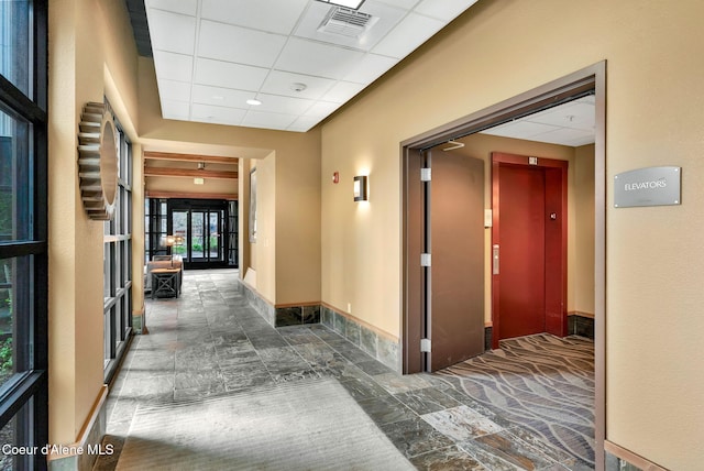 hallway with elevator, french doors, and a drop ceiling