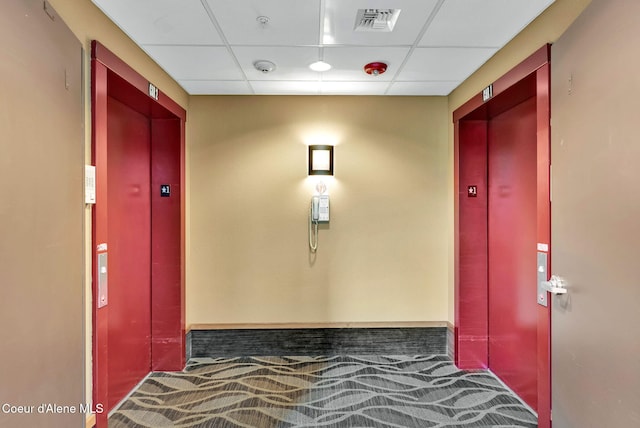 hall with a drop ceiling and carpet floors