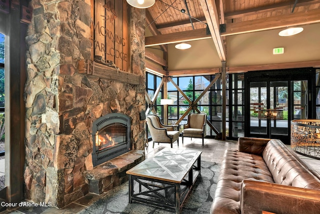 living room with a stone fireplace, beamed ceiling, and wood ceiling