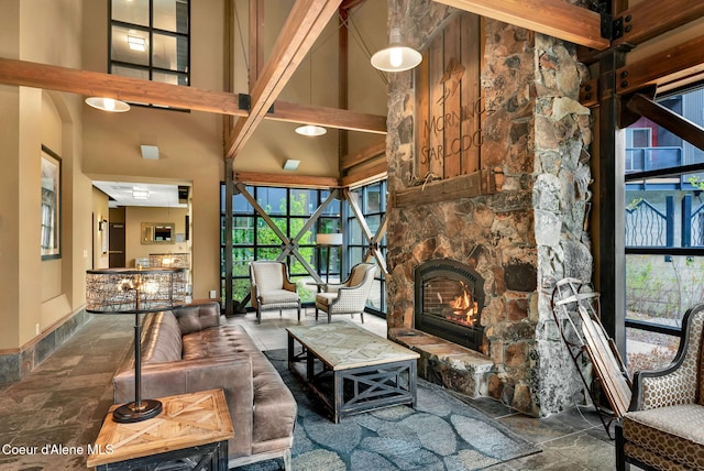 living room featuring a towering ceiling, a fireplace, and beam ceiling