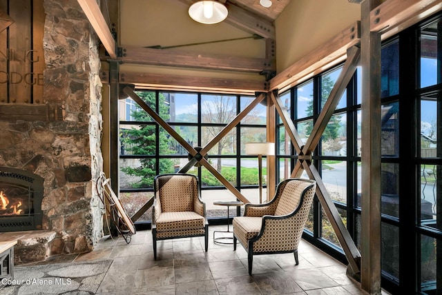 unfurnished sunroom with vaulted ceiling with beams and a fireplace