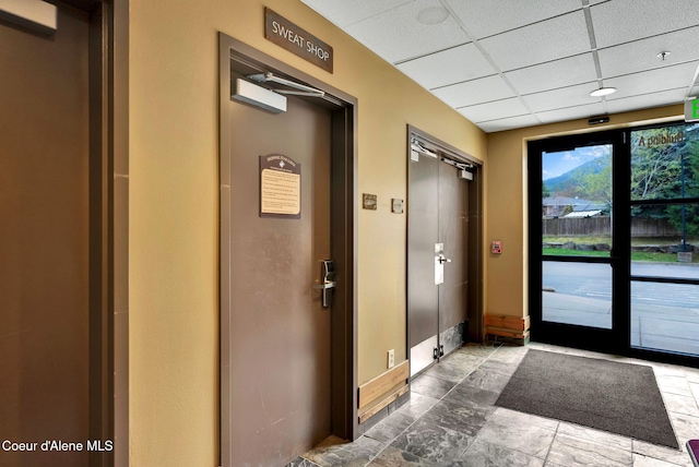 doorway to outside featuring a drop ceiling