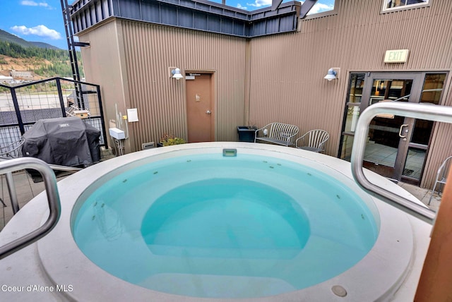 view of pool with an outdoor hot tub, grilling area, and a mountain view