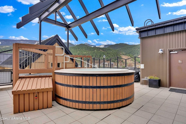 view of patio / terrace featuring a hot tub, a mountain view, and grilling area