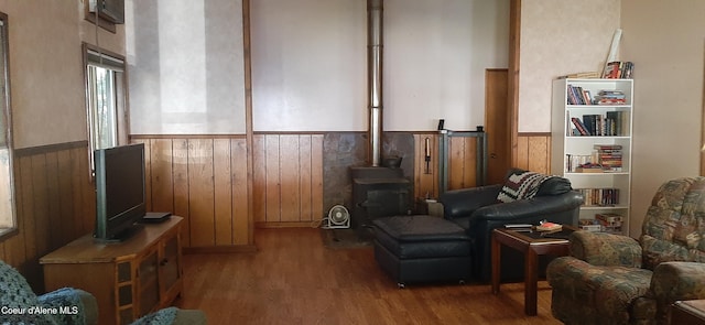 living area featuring hardwood / wood-style floors, wooden walls, and a wood stove