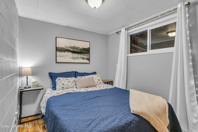 bedroom featuring wood-type flooring and ornamental molding