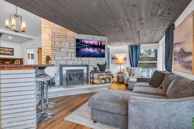 living room with wood ceiling, hardwood / wood-style flooring, an inviting chandelier, a fireplace, and lofted ceiling