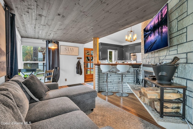 living room with wooden ceiling, a notable chandelier, wood-type flooring, vaulted ceiling, and a fireplace