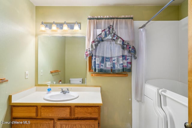 bathroom with a shower with shower curtain, vanity, toilet, and washer / dryer