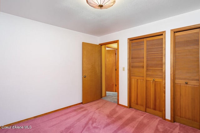 unfurnished bedroom featuring light carpet and multiple closets