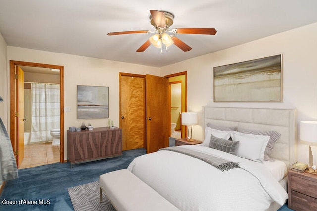 bedroom featuring ceiling fan, dark tile patterned floors, and ensuite bath