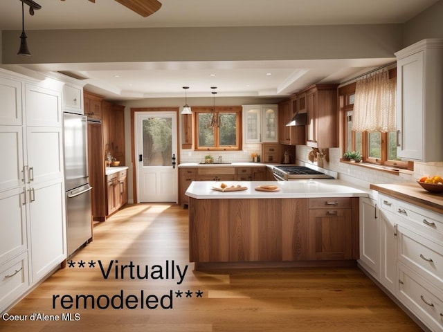 kitchen with a tray ceiling, white cabinetry, and decorative light fixtures