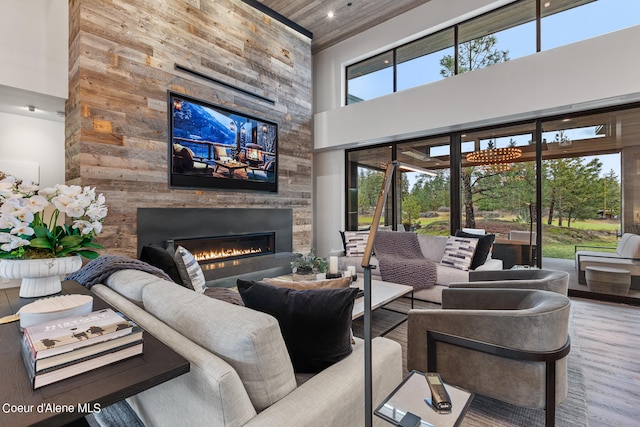 living room featuring wood-type flooring, wooden ceiling, a large fireplace, and a towering ceiling