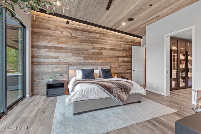 bedroom with light hardwood / wood-style flooring, wood ceiling, wooden walls, and vaulted ceiling