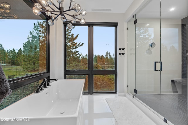 bathroom with an inviting chandelier, tile patterned floors, and a shower with shower door