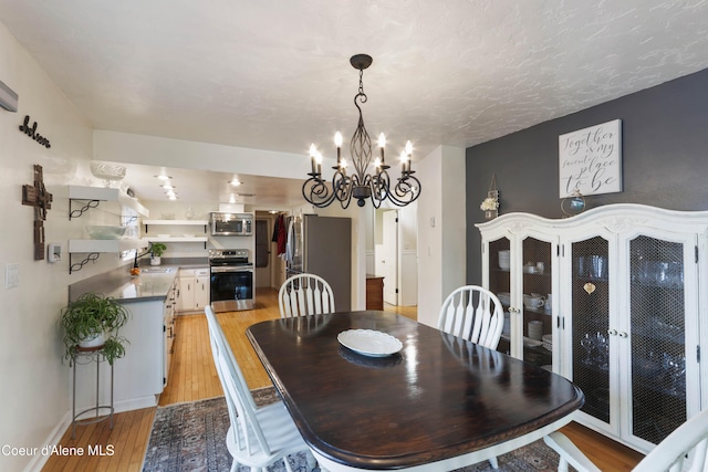 dining space featuring a chandelier, a textured ceiling, light hardwood / wood-style flooring, and sink