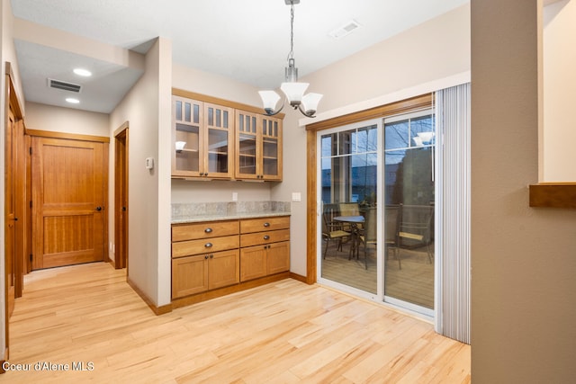 kitchen with light wood-type flooring, decorative light fixtures, and an inviting chandelier